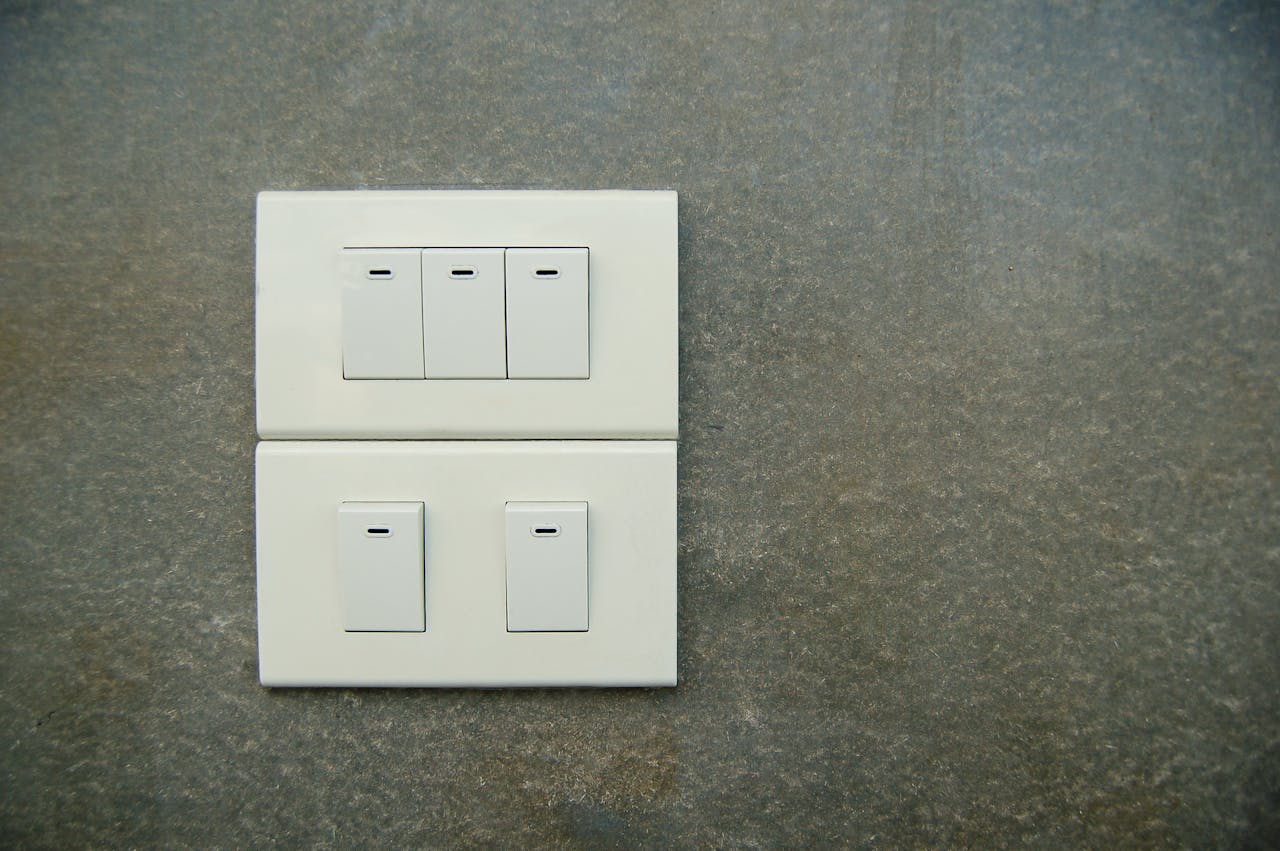 Minimalist photo of white electrical rocker switches on a textured stone wall background.